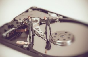 Miniature business people on top of hard drive. Business concept